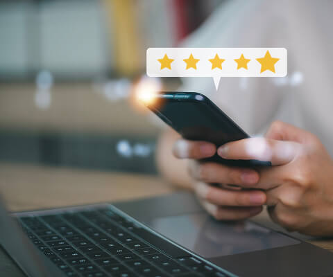 Somebody is so happy with their Newshosting subscription, you see a closeup of their hands leaving a review. Five yellow stars hover above the phone.