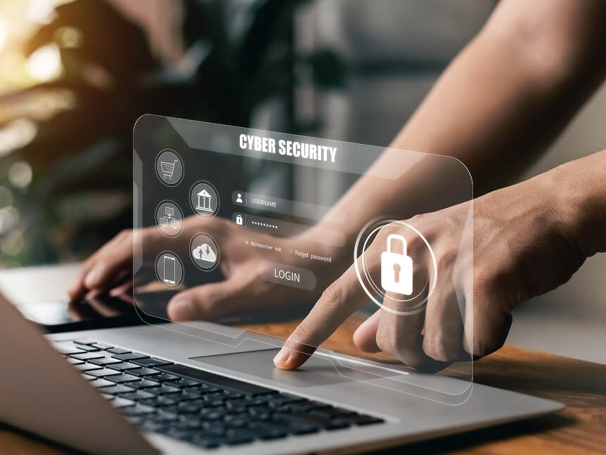 Closeup of a pair of hands. One is controlling the mouse with the touchpad and the other is holding onto a cellphone. A hologram hovers above the keyboard that reads “Cyber Security” and has a login screen.