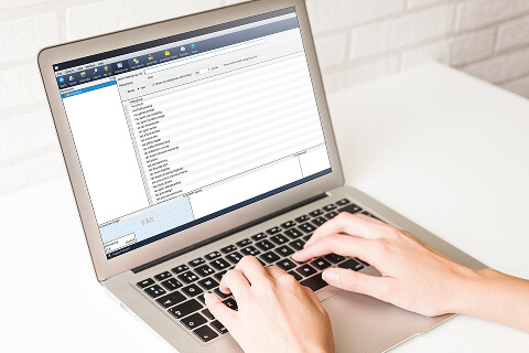 Closeup of a pair of hands typing on a laptop. The Newshosting Newsreader newsgroup search is on the screen.