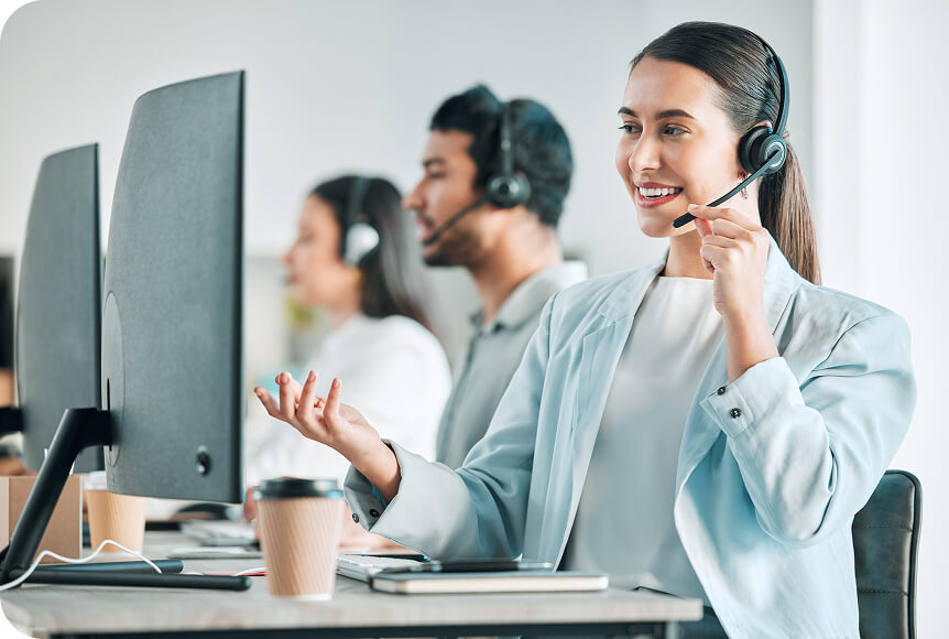 Three support staff are sitting at computers and speaking on headsets to Newshosting customers.